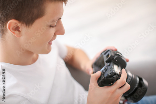 Teenage boy with photo camera at home