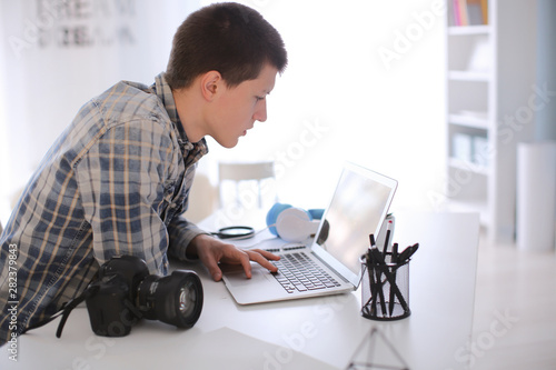 Teenage photographer working on laptop at home
