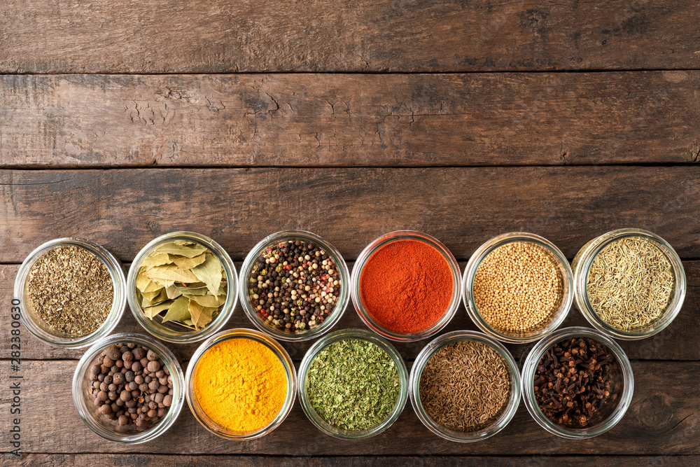 Colourful spices in bowls on wooden table with copyspace. Big collection of spices. Top view
