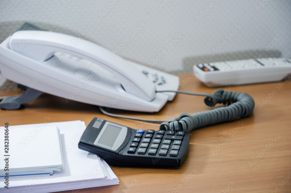 calculator, notepad and office phone on the table. Side view . Close-up. calculator, notepad and office phone on the table. Side view . Close-up.