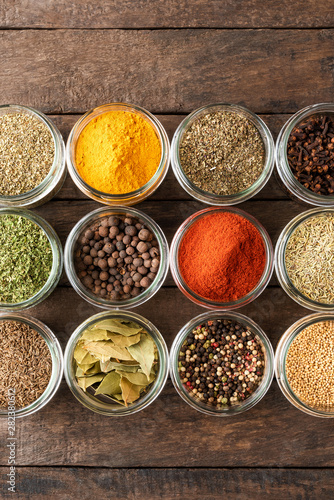 Various kinds of spices in bowls on wooden table. Top view