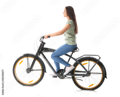 Beautiful young woman riding bicycle against white background