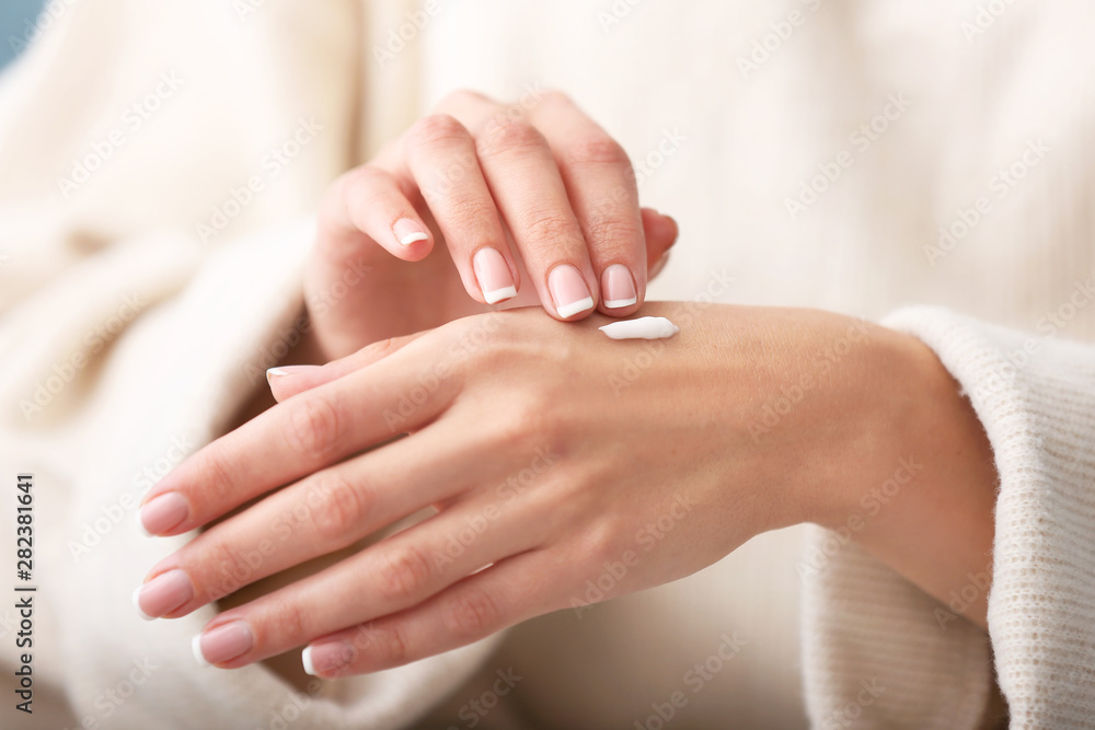 Naklejka premium Young woman applying natural cream onto skin at home, closeup