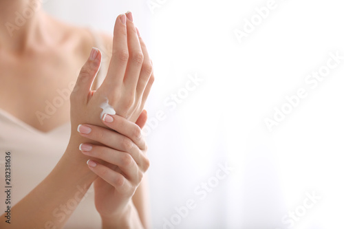 Fotografia Young woman applying natural cream onto skin at home