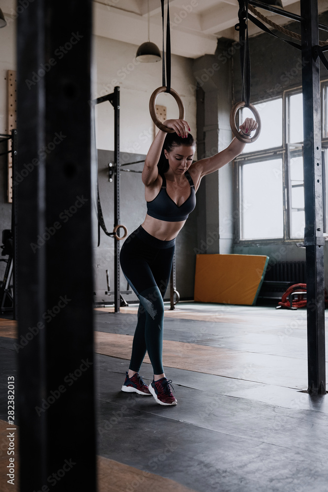 Fototapeta premium Happy healthy athletic woman laughing, resting after gymnastic rings workout