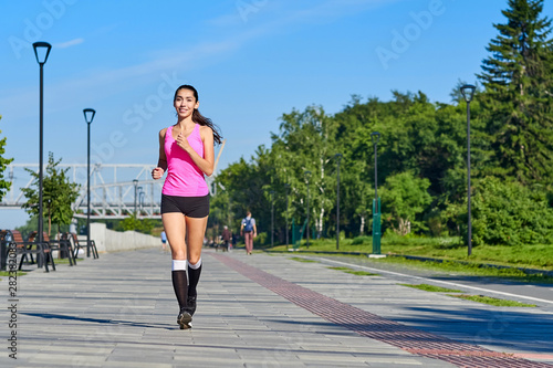 Running woman on the waterfront. Morning jogging. The athlete trains