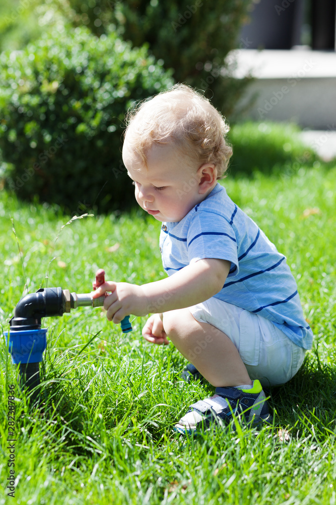 Portrait child boy playing with faucet.Concept of summer,childhood,leisure and for save water,conservative environment Portrait child boy playing with faucet.Concept of summer,childhood,leisure and for save water,conservative environment