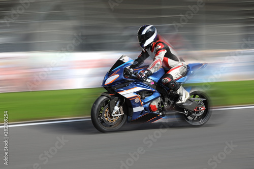 Obraz na plátně Motorcycle rider racing on race track with motion blur
