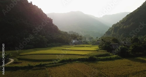 aerial dolly in shot over terraced rice fields between mountains in the early morning, approaching Lam thuong Valley farmhouses photo