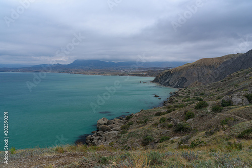 Black Sea coast on a cloudy day with clouds in the sky and a steep mountainside. .