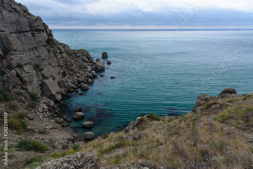 Black Sea coast on a cloudy day with clouds in the sky and a steep mountainside. .