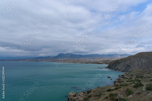 Black Sea coast on a cloudy day with clouds in the sky and a steep mountainside. .