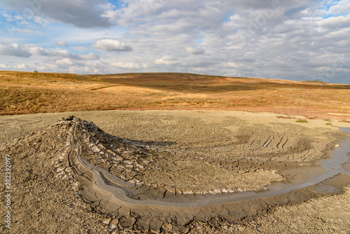 Mud volcano on the Crimean peninsula in sunny weather with clouds on the sky, shot during the season of golden autumn. Yellow-golden brown.