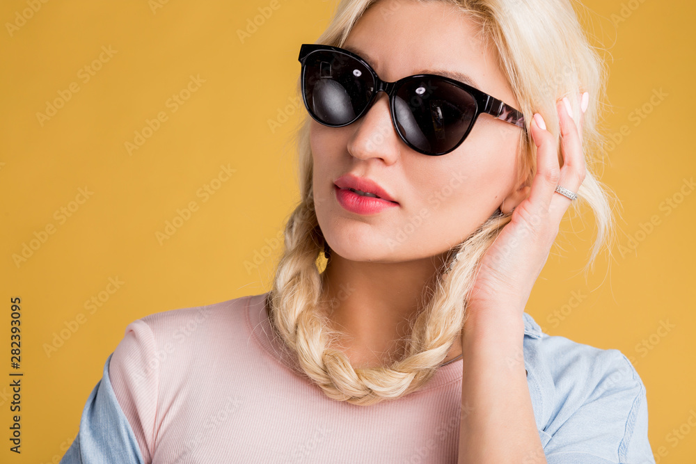Close up photo of beautiful woman in sunglasses isolated on yellow background Close up photo of beautiful woman in sunglasses isolated on yellow background