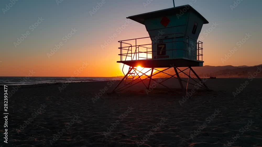 Slow crane shot rising up and revealing Lifeguard house : tower behind wooden log at sunset at San Buenaventura State Beach in Ventura, California, United States Slow crane shot rising up and revealing Lifeguard house : tower behind wooden log at sunset at San Buenaventura State Beach in Ventura, California, United States