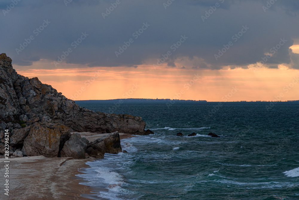 sunset on Generals beach of the Crimean peninsula on a sleepy day with clouds in the sky, shot during the season of golden autumn yellow-golden brown.