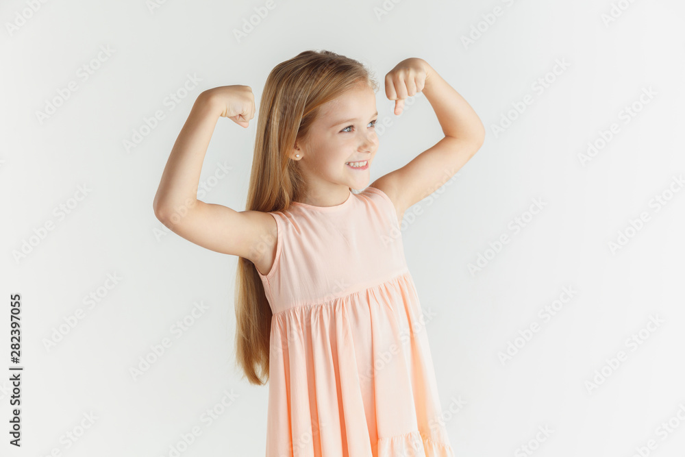 Stylish little smiling girl posing in dress isolated on white studio background. Caucasian blonde female model. Human emotions, facial expression, childhood. Winning, celebrating, looks happy. Stylish little smiling girl posing in dress isolated on white studio background. Caucasian blonde female model. Human emotions, facial expression, childhood. Winning, celebrating, looks happy.