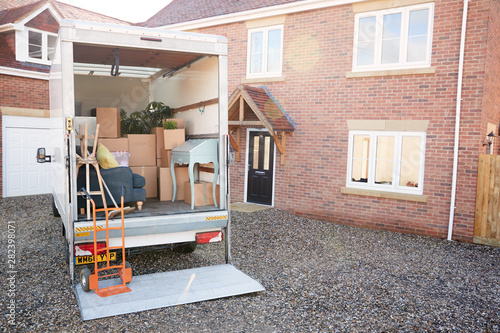 Removal Truck Waiting To Be Unloaded Outside New Home On Moving Day photo