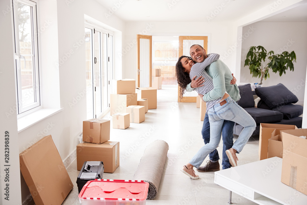 Loving Couple Hugging Surrounded By Boxes In New Home On Moving Day Loving Couple Hugging Surrounded By Boxes In New Home On Moving Day