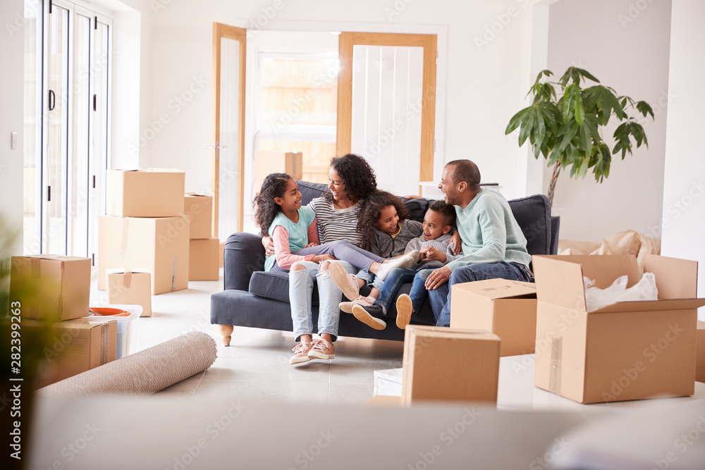 Family Taking A Break And Sitting On Sofa Celebrating Moving Into New Home Together Family Taking A Break And Sitting On Sofa Celebrating Moving Into New Home Together