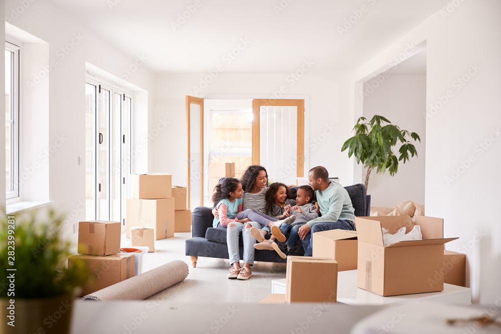 Family Taking A Break And Sitting On Sofa Celebrating Moving Into New Home Together Family Taking A Break And Sitting On Sofa Celebrating Moving Into New Home Together