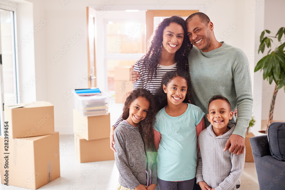 Portrait Of Family Surrounded By Boxes Standing In Room On Moving Day Portrait Of Family Surrounded By Boxes Standing In Room On Moving Day