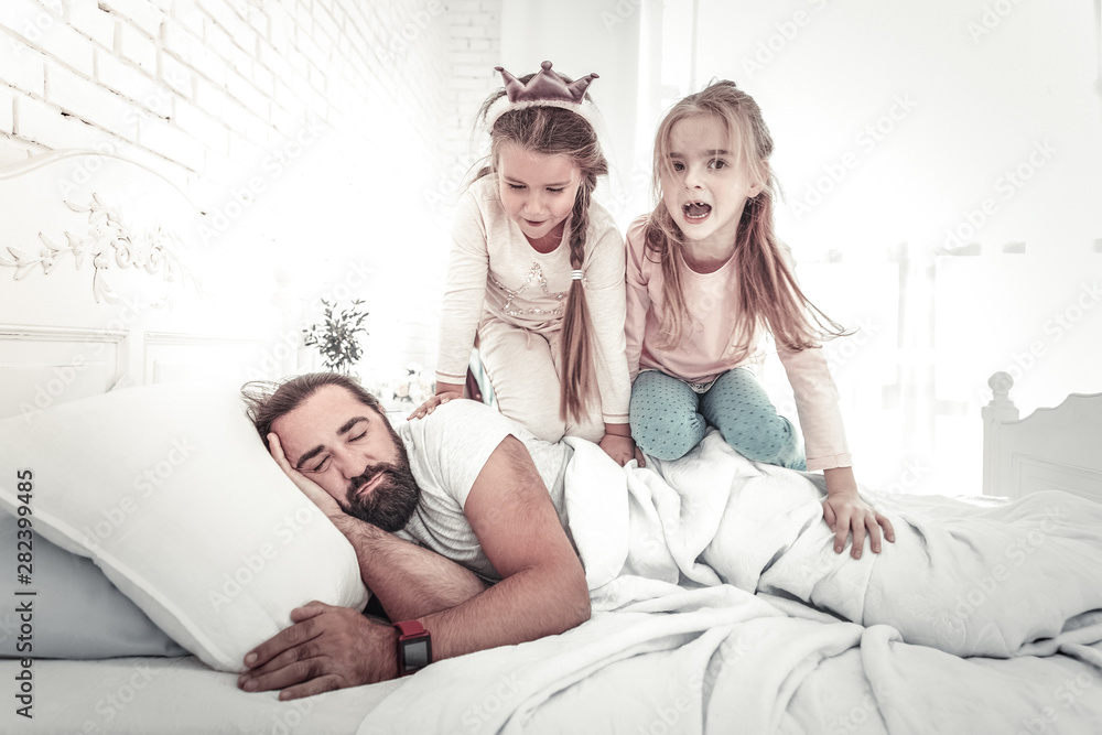 Daughters climbing their father to wake him up in bed Daughters climbing their father to wake him up in bed