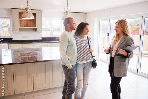 Female Realtor Showing Couple Interested In Buying Around House photo