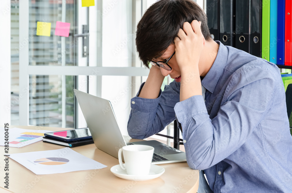 Young frustrated Asian businessman on his work and out of control. Stress and headache for job failure in office Young frustrated Asian businessman on his work and out of control. Stress and headache for job failure in office