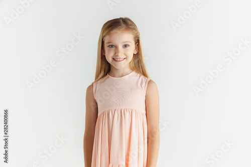 Tela Stylish little smiling girl posing in dress isolated on white studio background
