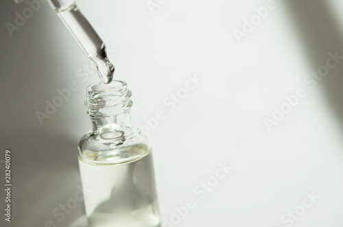 Cosmetic or medical glass bottle with pipette on white background. Skin care concept. Natural hard light, deep shadows. - Image