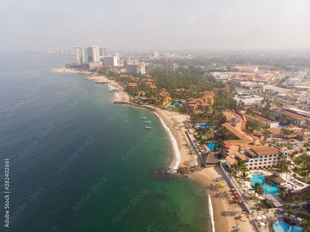Aerial photos of the beautiful beach and town of Puerto Vallarta in Mexico, the town is on the Pacific coast in the state known as Jalisco with the mountains in the background on a cloudy day.