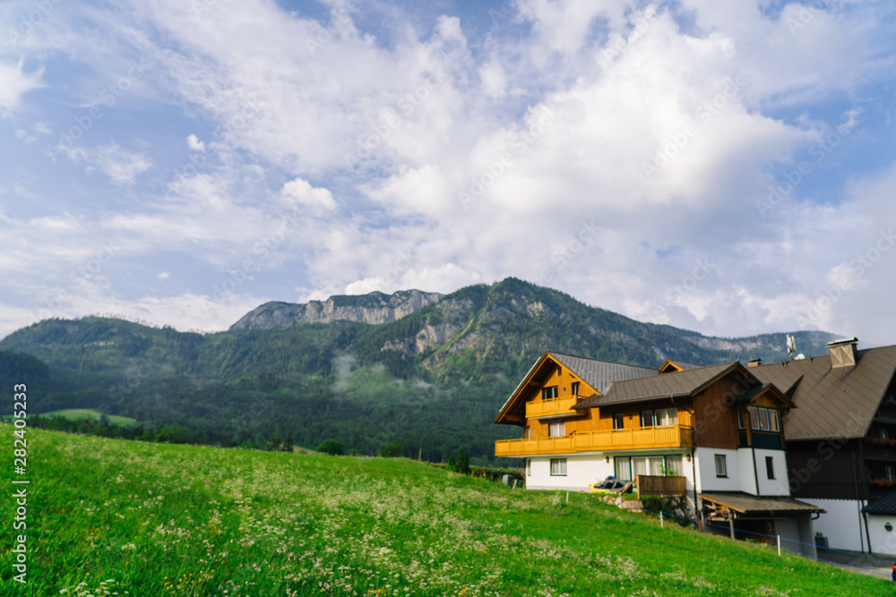 Fototapeta premium Morning in the Alps. Beautiful foggy morning scenery in Alps region, Austria. Great morning view of foggy mountains, fog, house and green meadow in Austria
