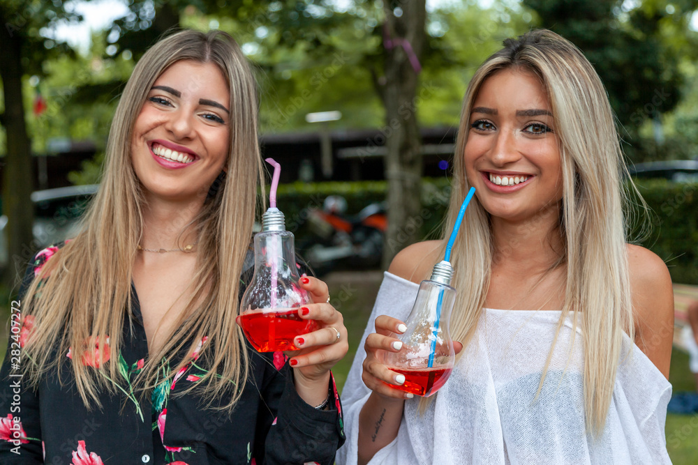 couple of young pretty women drinking fresh and energetic red juice couple of young pretty women drinking fresh and energetic red juice