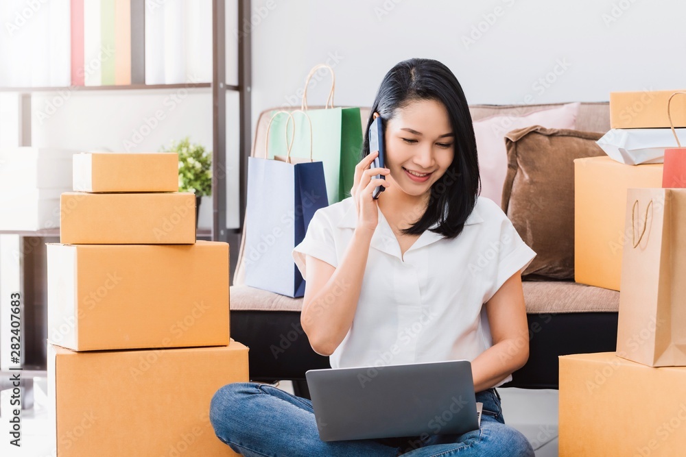 Asian beautiful woman working with smartphone to online business shop at home.Owner businesswoman start up with Accept orders,Check the number of products, Prepare to deliver products to customers. Asian beautiful woman working with smartphone to online business shop at home.Owner businesswoman start up with Accept orders,Check the number of products, Prepare to deliver products to customers.