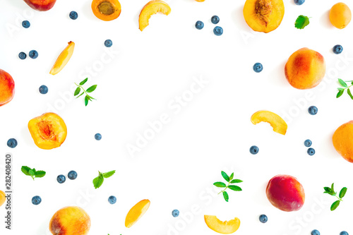 Fruit frame of ripe peaches, blueberies with mint leaves isolated on white background. Top view. Flat lay
