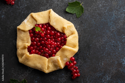 Homemade red currants tart with leaves. Vegetarian healthy galette decorated with fresh red currant. Delicious dessert.