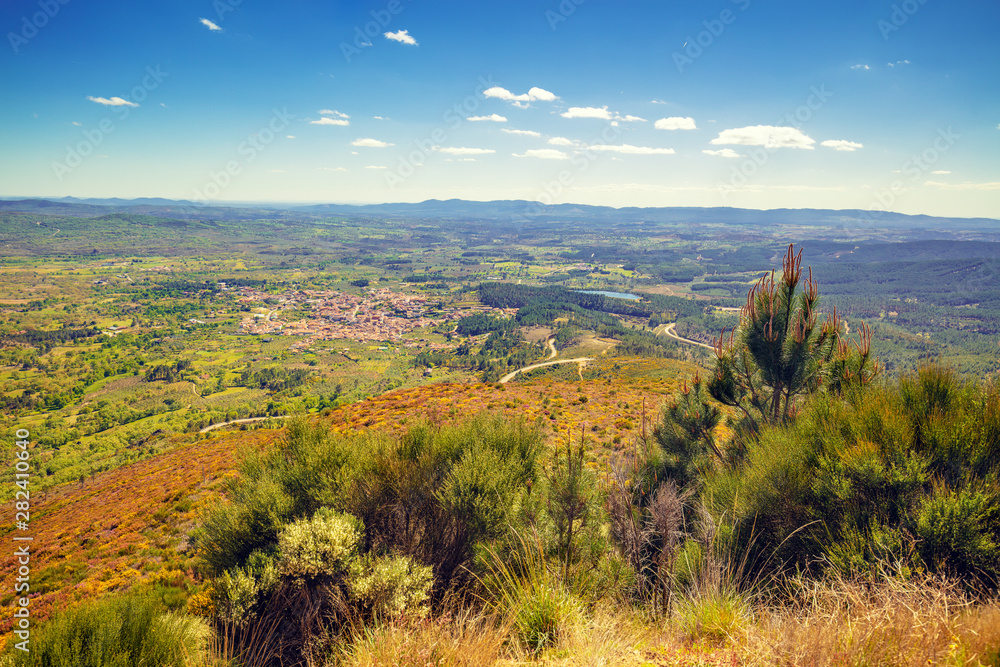 Fototapeta premium Panoramic landscape, view of valley, village in valley, mountains and fiels. Mountain landscape in early spring. Valverde del Fresno, Cáceres, Spain.