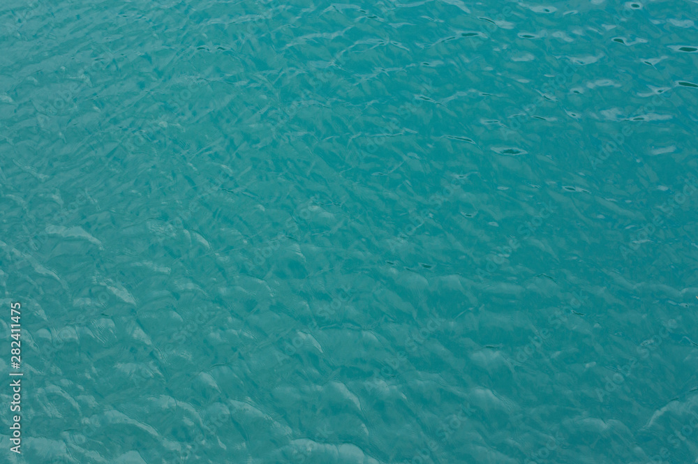 The surface of the water is gently turquoise with sunny reflections.