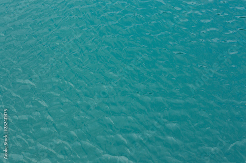 The surface of the water is gently turquoise with sunny reflections.