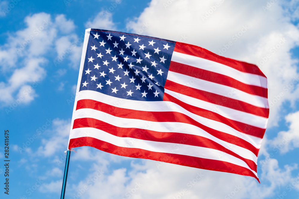 American flag on flagpole waving in the wind against white clouds American flag on flagpole waving in the wind against white clouds