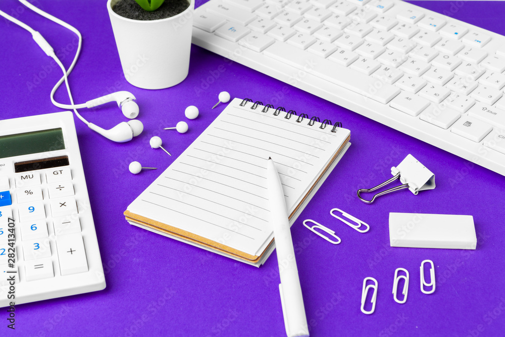 Composition of office lifestyle items on purple background, computer keyboard office supplies on desk in office Composition of office lifestyle items on purple background, computer keyboard office supplies on desk in office
