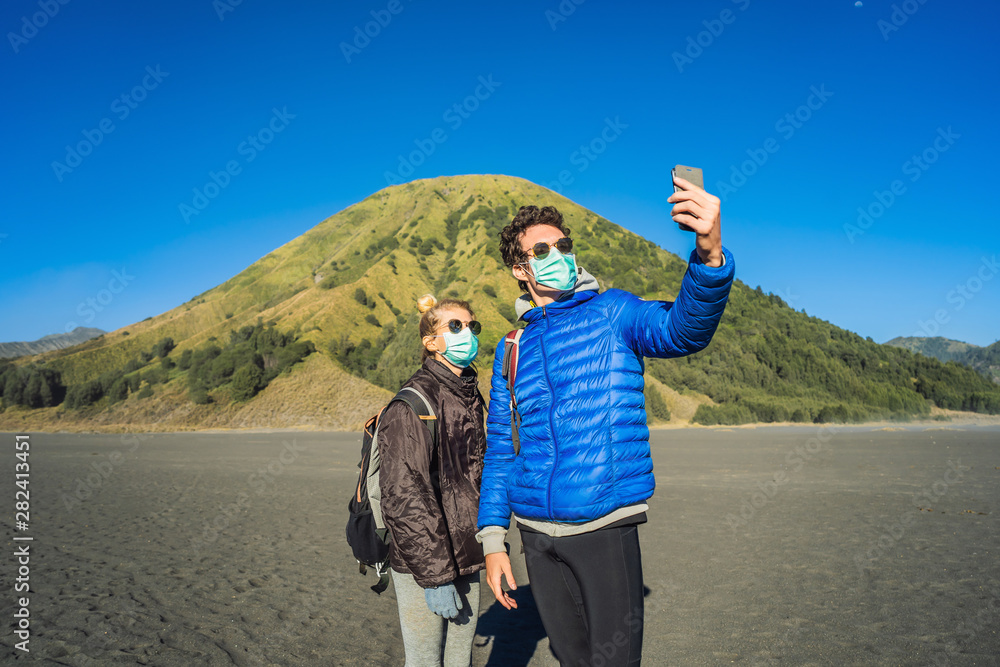 Young man and woman tourists make a selfie in the Bromo Tengger Semeru National Park on the Java Island, Indonesia. They enjoy magnificent view on the Bromo or Gunung Bromo on Indonesian, Semeru and
