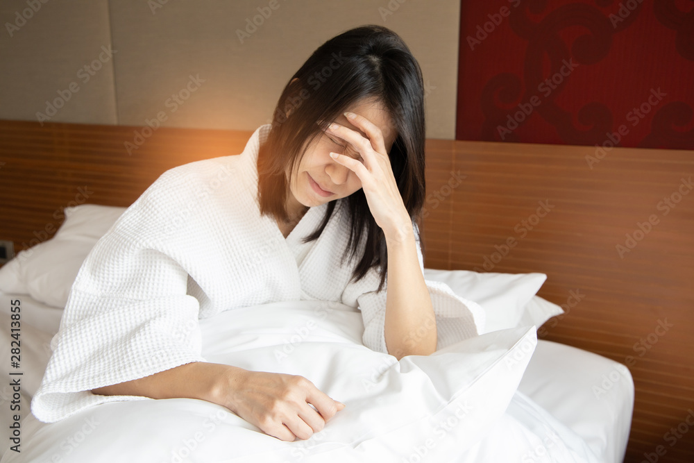 Woman stretching in bed after waking up, back view. Woman sitting near the big white window while stretching on bed after waking up with sunrise at morning, back view. Woman stretching in bed after waking up, back view. Woman sitting near the big white window while stretching on bed after waking up with sunrise at morning, back view.