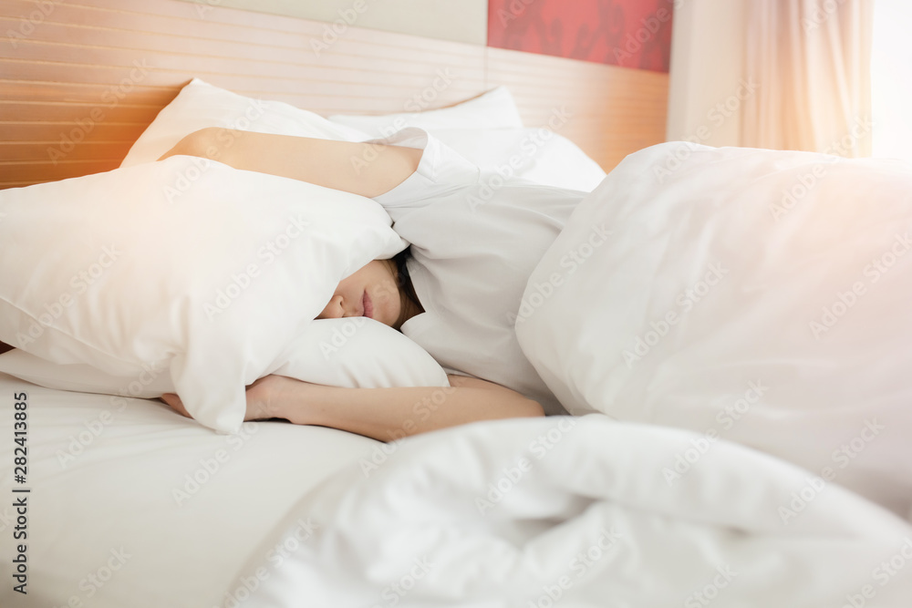 Woman stretching in bed after waking up, back view. Woman sitting near the big white window while stretching on bed after waking up with sunrise at morning, back view. Woman stretching in bed after waking up, back view. Woman sitting near the big white window while stretching on bed after waking up with sunrise at morning, back view.