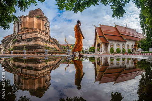 Obraz na plátně CHIANG MAI , THAILAND- AUGUST 2, 2019 : Novice is walking to study against Pagoda and reflection at Wat Chedi Luang Temple in Chiang mai, Thailand