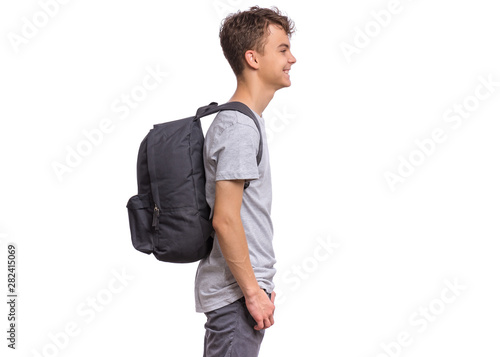 Student teen boy with backpack - side view. Portrait of cute smiling schoolboy with hands in pockets, isolated on white background. Happy child Back to school - profile.