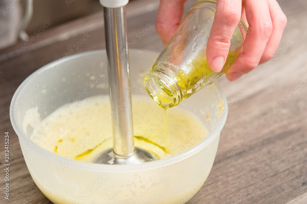 close-up whipping the mixture of homemade mayonnaise with a blender in a plastic bowl. olive oil close-up whipping the mixture of homemade mayonnaise with a blender in a plastic bowl. olive oil