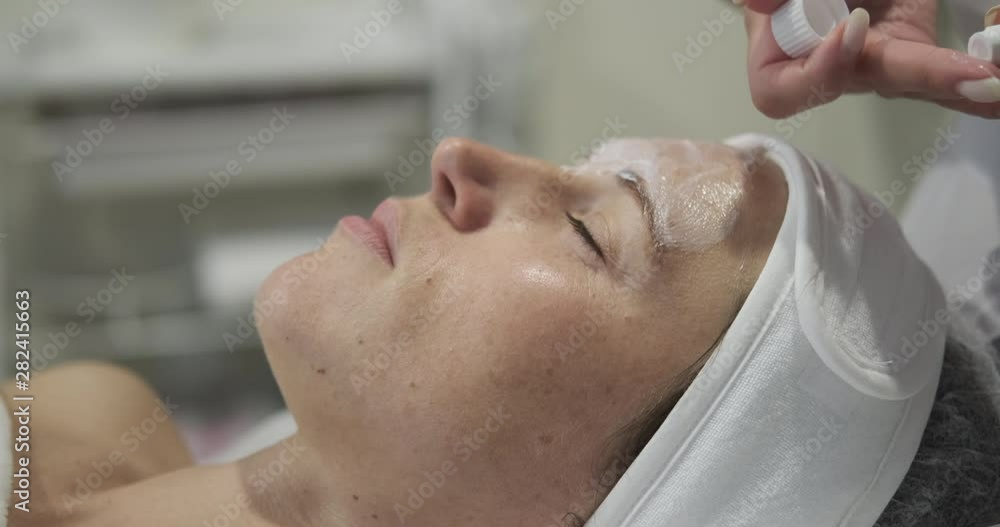 Cosmetologist applying face cream to woman customer at spa salon Cosmetologist applying face cream to woman customer at spa salon