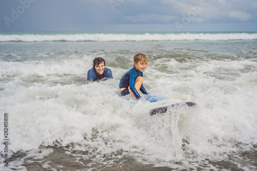 Sticker Father or instructor teaching his 5 year old son how to surf in the sea on vacation or holiday